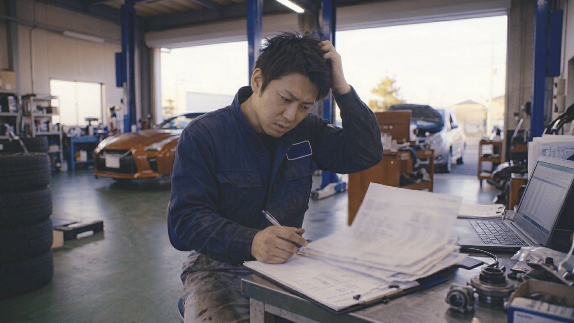 整備場工場経営者の男性が悩んでいるイメージ